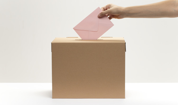 une-main-met-une-enveloppe-rose-dans-la-boite-de-vote.jpg